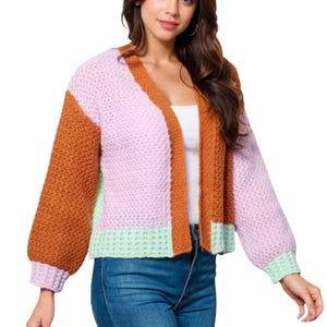 A knit colorblock cardigan featuring a mix of orange, pink, and mint green hues with a textured pattern. It has a relaxed fit, long sleeves, and an open front.