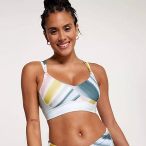 A woman is wearing a sports bra with a pastel abstract design and a matching bottom.