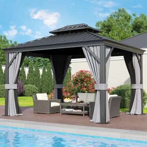 12' x 10' metal gazebo with a dark roof, light and dark curtains, placed on a poolside deck. Contains wicker furniture including cushioned chairs and a coffee table, surrounded by bushes and trees.