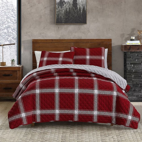 A red and white plaid bedding set on a bed, complete with pillows and a quilt.