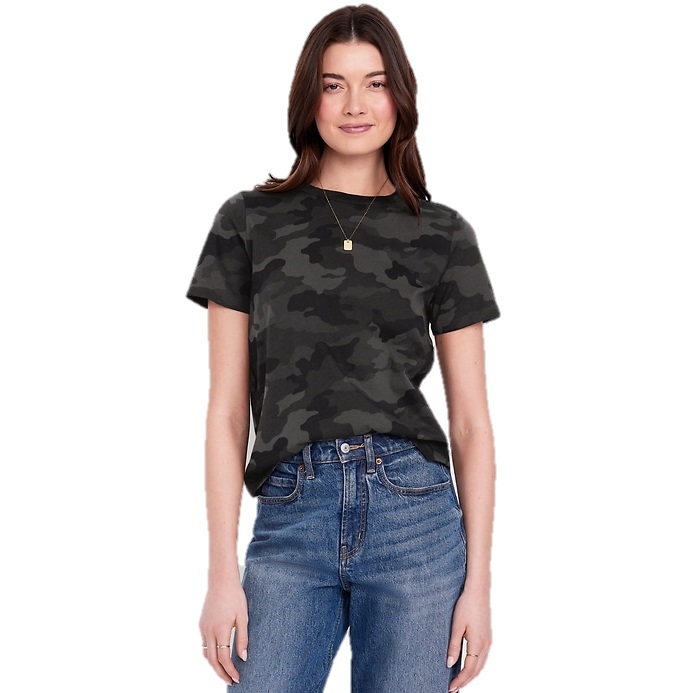 A woman wearing a dark camouflage-patterned T-shirt and blue high-waisted jeans. She has a necklace with a small square pendant.