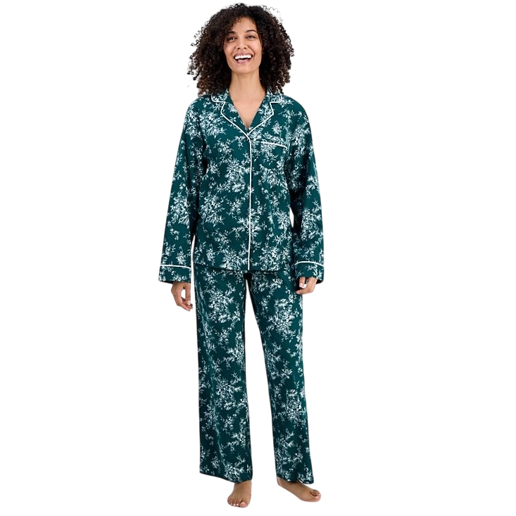 A person wearing a green pajama set with a white floral pattern and contrasting piping, featuring a long-sleeve button-up top and matching pants.