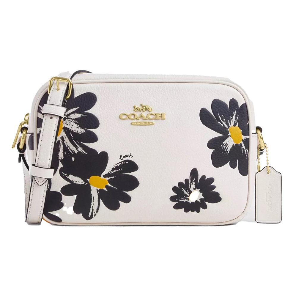 White Coach crossbody bag with black and yellow floral design and gold-tone hardware.