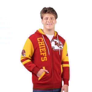 A man is wearing a red and yellow full-zip hooded sweatshirt with the \“CHIEFS\“ logo and team's emblem on the front.