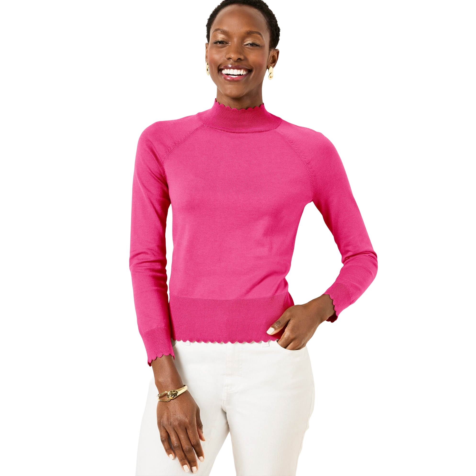 A person is wearing a bright pink long-sleeve sweater with scalloped edges and white pants. They also have a gold bracelet and small earrings.