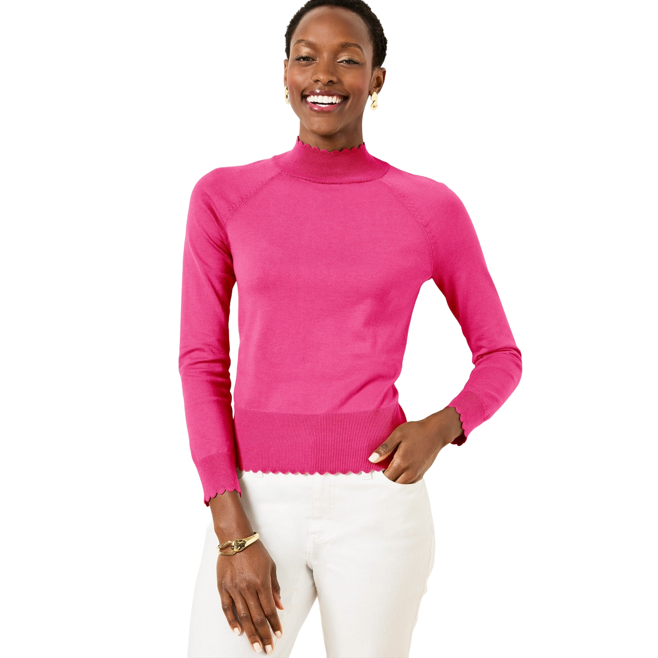 A person is wearing a bright pink long-sleeve sweater with scalloped edges and white pants. They also have a gold bracelet and small earrings.