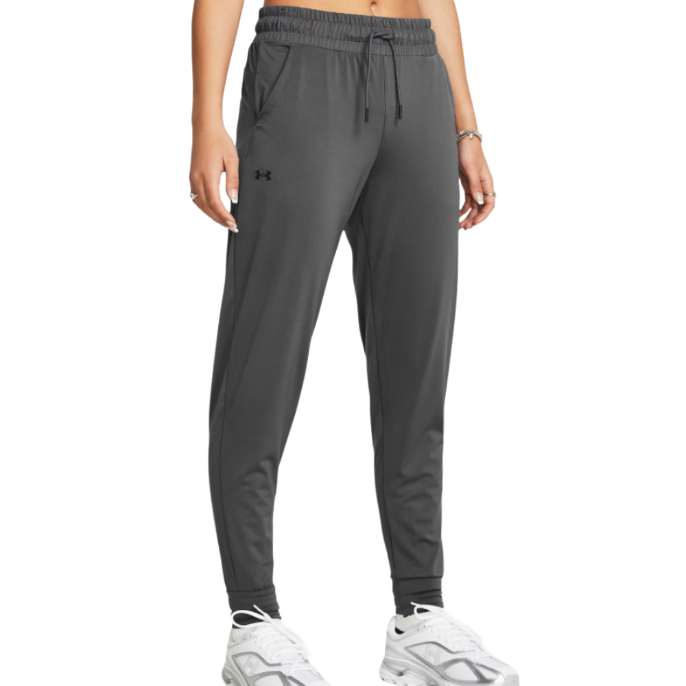Dark gray jogger pants with an elastic waistband and drawstring, featuring the Under Armour logo, paired with white sneakers.