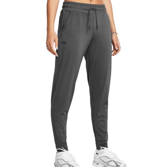Dark gray jogger pants with an elastic waistband and drawstring, featuring the Under Armour logo, paired with white sneakers.