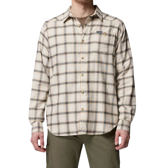 A man is wearing a long-sleeve, button-up plaid shirt in beige with green and dark blue lines, paired with olive green pants.