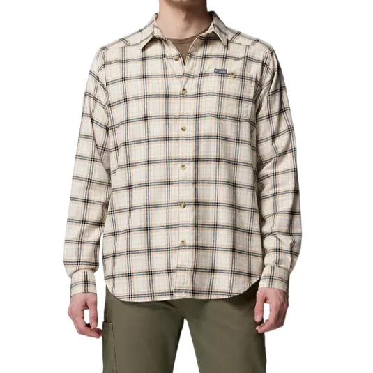 A man is wearing a long-sleeve, button-up plaid shirt in beige with green and dark blue lines, paired with olive green pants.