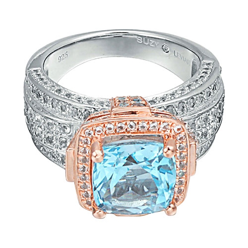 A sterling silver and rose gold-tone ring featuring a large blue cushion-cut gemstone, surrounded by smaller clear stones.