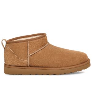 UGG Shaggy Boots are ankle-high, tan footwear with a suede exterior and plush lining, featuring visible stitching and a loop at the back. They have a flat sole with a grip pattern for traction.