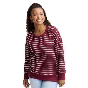 A woman is wearing a maroon sweater with white horizontal stripes paired with light blue jeans.