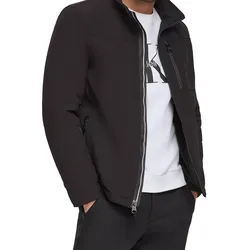 A man is wearing a black zip-up jacket with a stand collar over a white shirt and black pants, featuring zippered pockets.