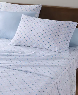 A bed with a floral blue and white patterned sheet set, including pillowcases and a fitted sheet.