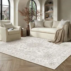 A beige sofa and armchair set with matching cushions and a beige patterned rug are arranged in a bright room with arched windows, wooden shelving, and a herringbone-patterned wood floor.