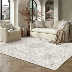 A beige sofa and armchair set with matching cushions and a beige patterned rug are arranged in a bright room with arched windows, wooden shelving, and a herringbone-patterned wood floor.