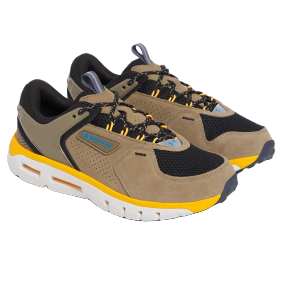 UA Men's Summit Trek Shoes are tan and black with yellow accents, featuring a perforated upper, durable lace hooks, and a thick white sole with orange detailing for enhanced comfort and support.