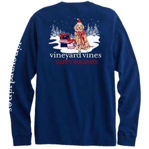 Navy long-sleeve t-shirt featuring a holiday-themed graphic with a dog wrapped in lights next to presents and the text \“vineyard vines HAPPY HOLIDAYS.\“