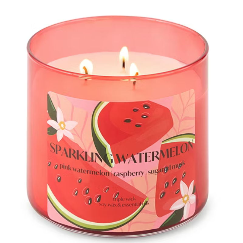 A triple-wick candle in a pink glass container labeled \“Sparkling Watermelon,\“ featuring scents of pink watermelon, raspberry, sugar, and musk.