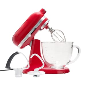 A red KitchenAid Mini Stand Mixer with a glass mixing bowl and three attachments: a wire whisk, a flat beater, and a dough hook.