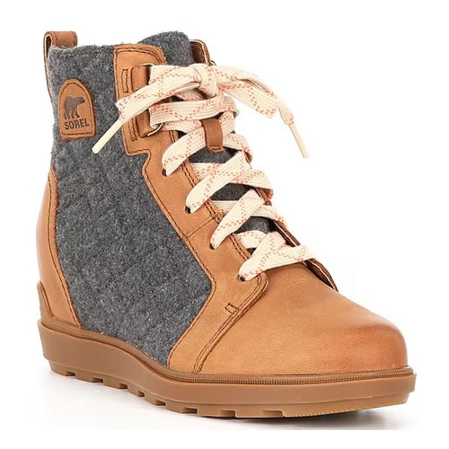 Sorel lace-up booties feature tan leather with gray felt panels, cream laces, and a logo patch on the side. They have a sporty, casual style with a sturdy sole for traction.