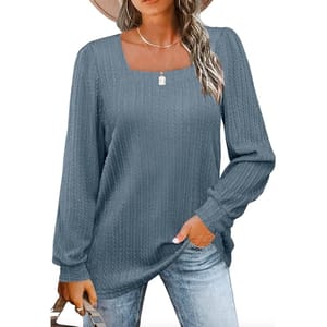 A woman is wearing a long-sleeved, ribbed-knit top in a solid grey color with a relaxed fit and a round neckline. The top is paired with blue jeans.