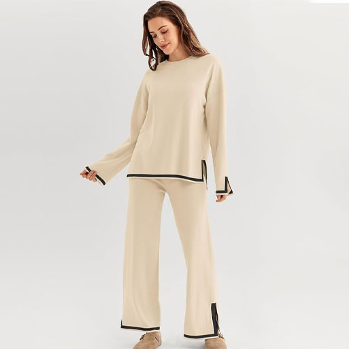A woman is showcasing a beige loungewear set with black trim details on the top and pants.