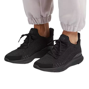 A pair of black knit sneakers with black soles, worn with light-colored jogger pants.