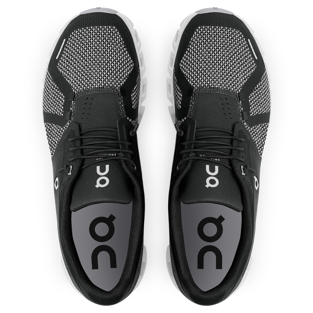 A pair of black athletic shoes with white soles viewed from above.