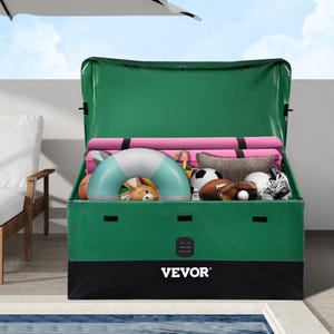 A green 100-gallon Vevor storage box, filled with items like a pink yoga mat, inflatable ring, stuffed toy, and various sports balls, is situated next to a pool and lounge chair.