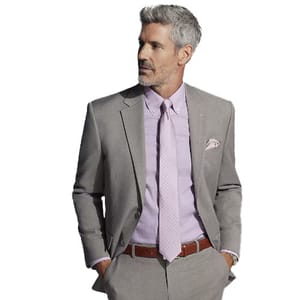 A man sports a modern fit gray windowpane suit with a subtle check pattern, paired with a light pink dress shirt and a matching tie. The outfit includes a coordinating pocket square and brown belt.