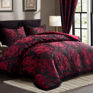 A black and red floral-patterned bedding set includes a comforter and pillow shams, with matching curtains in a bedroom setting.