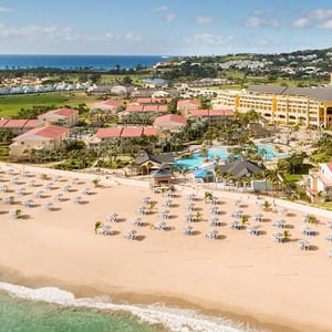 Aerial view of a beachfront resort with pools, sun loungers, and umbrellas.