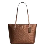 Brown Coach tote bag with signature logo pattern, featuring gold-tone hardware and long handles.