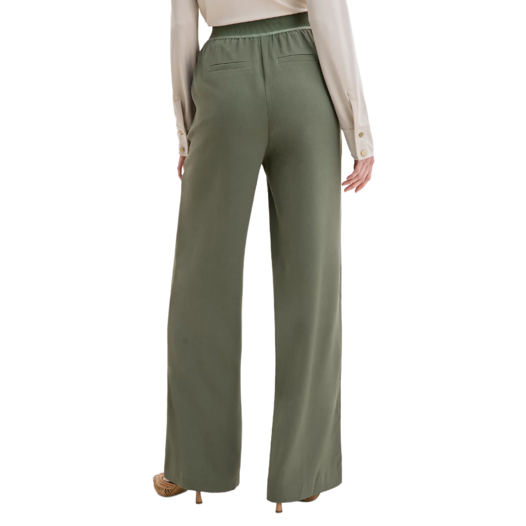 A person is wearing olive green, wide-leg pants with an elastic waistband and two back pockets, paired with a long-sleeve, cream-colored blouse with buttoned cuffs.