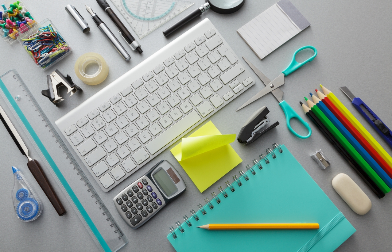 Office supplies including a keyboard, calculator, colorful pens and pencils, notebook, scissors, and adhesive tape.