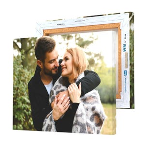 A canvas print featuring a couple embracing in an outdoor setting, wrapped in a cardboard frame with a barcode and text indicating it's a canvas product.