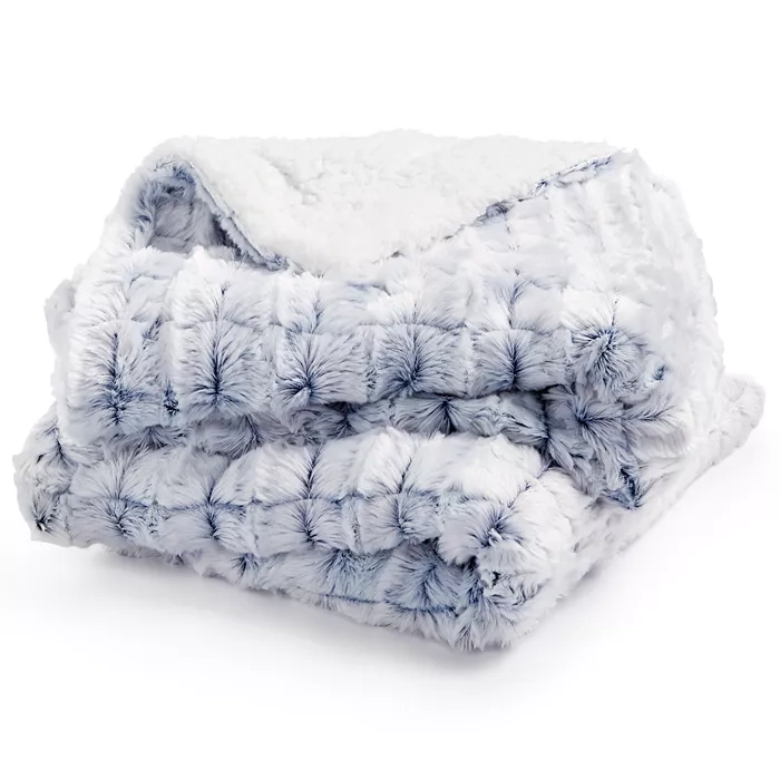 A plush, folded faux fur blanket with a textured, tufted surface in gray and white, featuring a soft, sherpa-like lining.