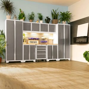 7-piece NewAge garage system features sleek gray cabinets with white frames, high and low storage units, a workbench, drawers on wheels, and overhead cabinets, all surrounded by potted plants on top for a tidy, organized workspace.