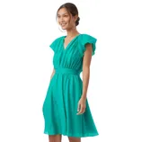 A woman models a teal dress featuring ruffled sleeves and a gathered waist. She pairs it with gold strappy high-heeled sandals.
