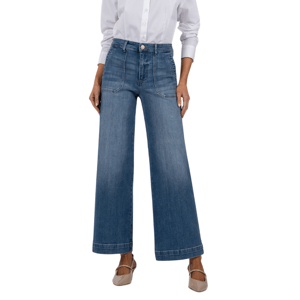 Wide-leg denim jeans with front pockets and a high waist, paired with a white button-up shirt and beige heels.