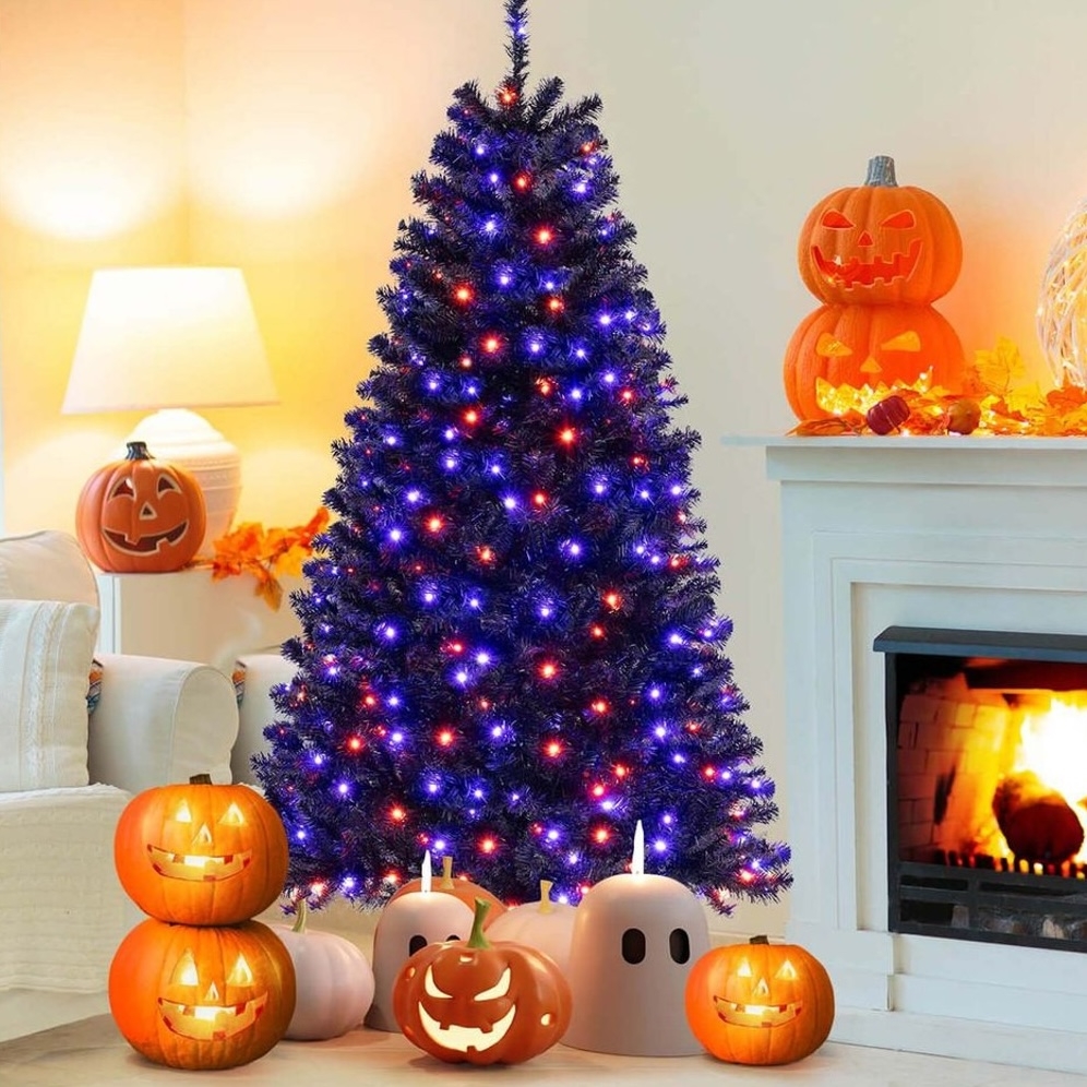 A black Christmas tree with purple and orange lights is surrounded by lit jack-o'-lanterns and ghost decorations, placed near a fireplace and other Halloween-themed decor.