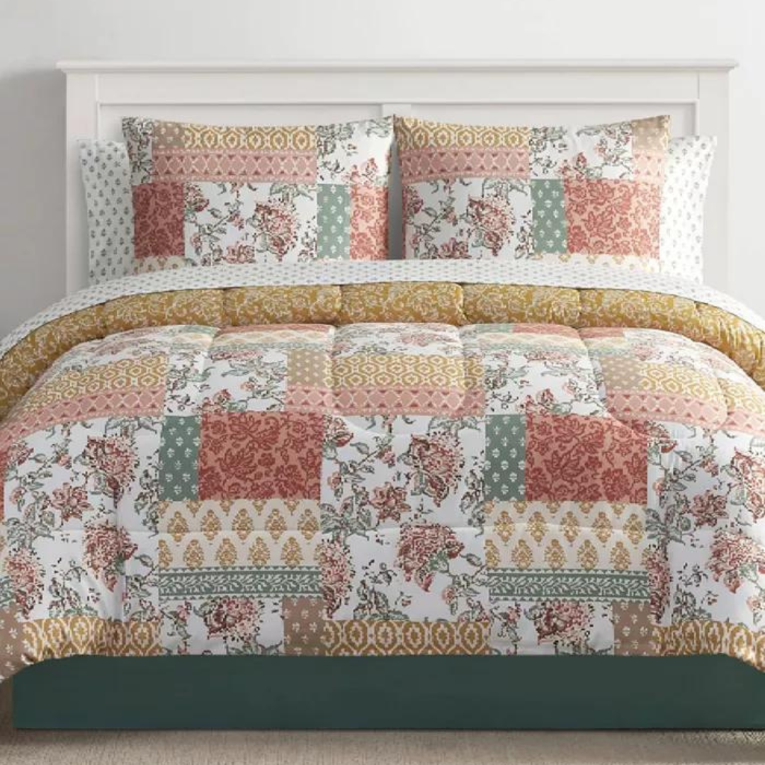 A patchwork-style comforter set featuring various patterns in shades of red, green, and cream, with coordinating pillows and sheets.