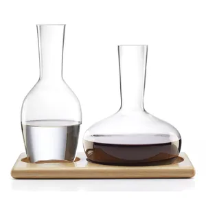 Two glass carafes sit on a wooden tray, one filled with water and the other with red wine.