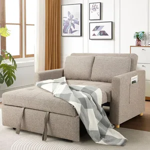 A stylish beige sofa bed with a checkered blanket draped over it, featuring storage space and side pockets. Wall art and indoor plants enhance the cozy living room setting.