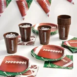 Football-themed party supplies including cups, plates, napkins, and banners, all featuring designs resembling footballs and fields.