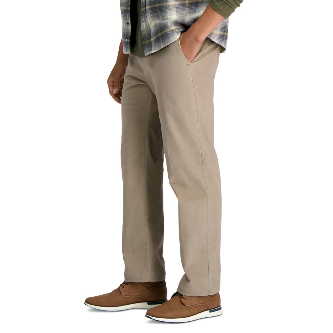 A person is wearing beige chinos paired with brown casual shoes and a plaid shirt layered over a green top.