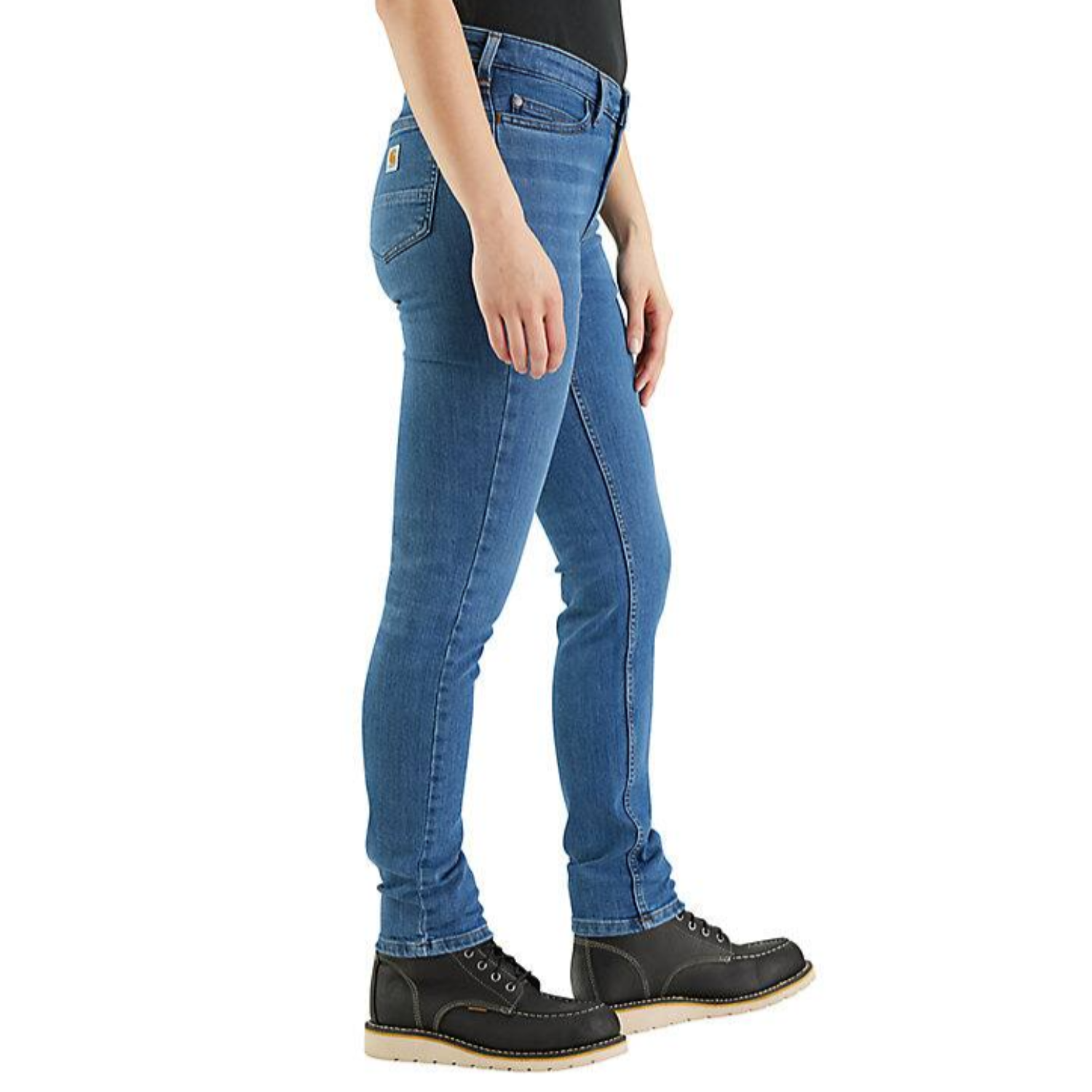 Carhartt Mid Rise Jeans are blue, slim-fitting, and feature classic pocket styling. They're paired with black work boots with a light-colored sole.