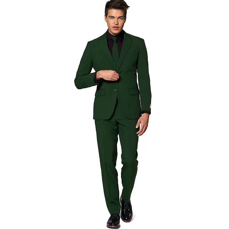 A man is wearing a dark green suit with a black shirt and tie, paired with black dress shoes.